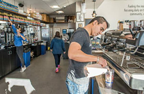 A man makes iced coffee behind the counter at a coffee shop